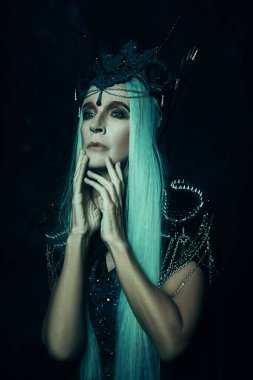 Peri masalı kötü Kraliçe, Cadı. Uzun açık turkuaz saçlı, zengin başlıklı ve koyu arkaplanlı zengin siyah elbiseli görkemli ve güzel bir kadının portresi. Cadılar Bayramı.