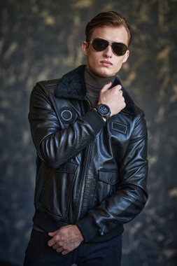 Erkek tarzı. Arkaplanda siyah deri ceketli ve güneş gözlüklü yakışıklı bir adamın portresi..