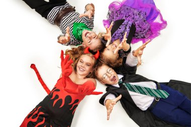 Cadılar Bayramı kostümü giymiş bir grup şirin çocuk beyaz zeminde elleri havada mutlu bir şekilde poz veriyorlar. Mutlu Cadılar Bayramı! Boşluğu kopyala.