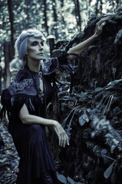 Güzel gri saçlı ve zengin siyah elbiseli aristokrat bir dul kadın mezarlıktaki bir mahzende üzgün poz veriyor. Kara Dul. Gizemciliğin atmosferi. Cadılar Bayramı.