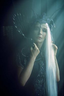 Çekici, görkemli, siyah bir kontes, zengin bir başlık ve siyah elbiseyle, karanlığın içinde ışığın altında duruyor. Hayal Dünyası. 