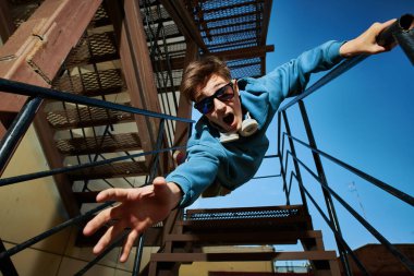 Aktif modern genç nesil. Duygusal çocuk mavi gökyüzüne karşı merdivenlerden kameraya doğru atlar ve bağırır:.