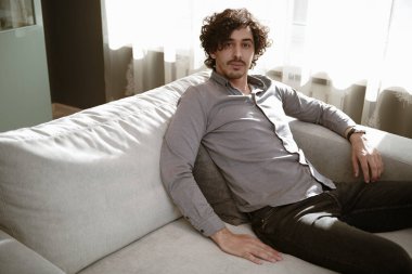 Oturma odasındaki kanepede rahat rahat rahat giyinen yakışıklı bir adam. Mutlu insanlar ve yaşam tarzı konsepti.