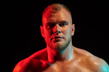 Siyah arka planda, çok renkli ışıklandırmada güçlü bir kızıl saçlı atletik adamın portresini yakından çek. Erkek güzellik konsepti. 