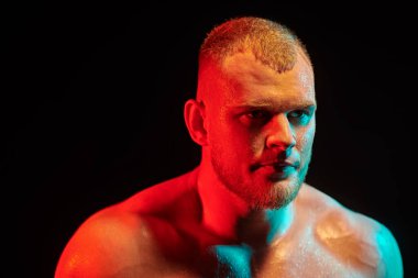 Çok renkli ışıklandırmada siyah arka planda antrenman yaparken terleyen sporcu portresi. Yan görüş. Erkek güzellik konsepti. 