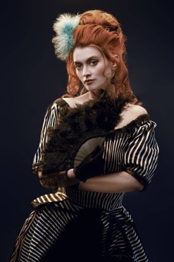 Koyu arkaplanda Victoria tarzı makyaj ve saç stili olan güzel kızıl saçlı bir kadının portresi. 19. yüzyılın modası..