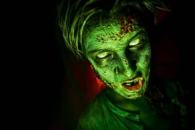 Karanlıkta yeşil ışıklı korkunç zombi bir gencin yakın plan portresi. Cadılar Bayramı, korku filmi. 