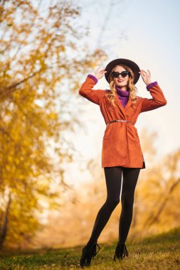 Güzel genç bir kadın sonbahar parkında yürüyor ve gülümsüyor. Sonbahar güzelliği, moda. Tam boy portre.