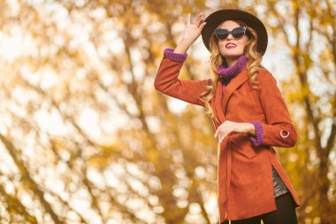 Şapkalı, gülen güzel bir genç kadının portresi sonbahar ağaçlarının arka planında. Güzellik, moda. Sonbahar mevsimi. 