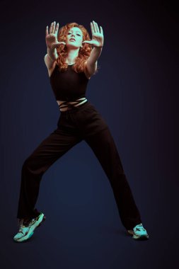 Modern dans. Stüdyoda koyu mavi arka planda dans eden profesyonel bir modern dansçı kızın tam boy portresi..