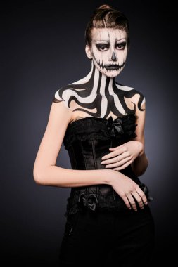 Siyah arka planda balkabağı kafatası makyajı olan zarif bir kadın. Cadılar Bayramı. Ölüler Günü. Boşluğu kopyala.