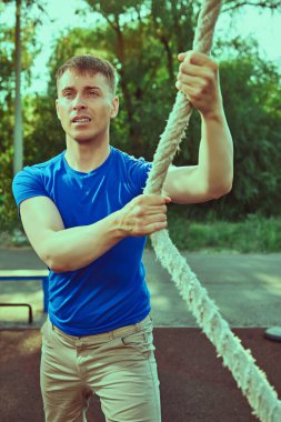 Atletik adam parktaki sokak spor salonunun ipine tırmanır. Spor salonunda çalışıyorum.. 