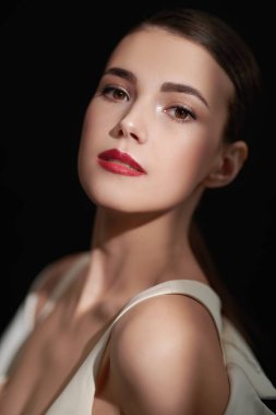 Siyah arka planda bir ışık demetinde duran gece makyajlı zarif esmer bir kadının portresini yakından çek. Makyaj ve kozmetik.