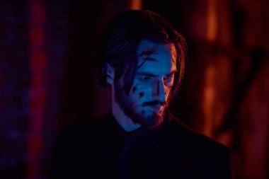 Yaralı bir aksiyon kahramanının portresi. Yüzünde kanlı yaralar var. Şehrin çok renkli ışıklarıyla.. 