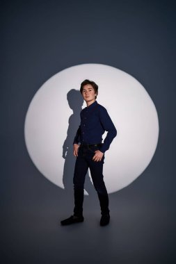 Stüdyoda ışık çemberindeki yakışıklı bir gencin tam boy portresi. Gençlik modası.