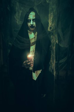 Korku ve Cadılar Bayramı. Terk edilmiş kilisede elinde mumla duran lanetli bir rahibenin portresi..