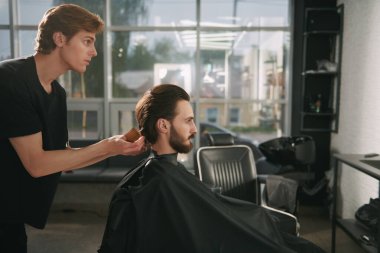 Saç kesimini mükemmel gösteriyor. Yakışıklı esmer adam berber dükkanını ziyaret ediyor..