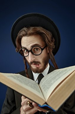 Tevrat okuyan duygusal bir Ortodoks Yahudi 'nin portresi. Stüdyo çekimi koyu mavi arkaplanda. 