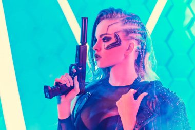 Bilim kurgu siborg asker kız. Çekici bir siber punk kız neon ışıkların arasında elinde silahla tetikte bekliyor. Geleceğin dünyası. Oyun, sanal gerçeklik.