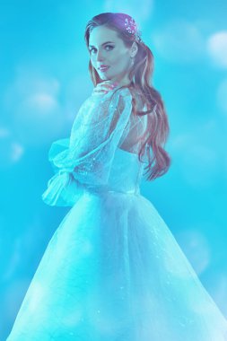 Düğün modası. Lüks beyaz elbiseli, yumuşak mavi ışıkta güzel bir gelinin portresi. Düğün makyajı ve saç stili.