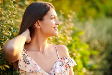 Güzel romantik bir kız batan güneşe bakar ve mutlu bir şekilde gülümser. Yaz modası ve güzellik. Yaz zamanı..