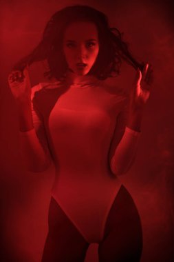 Çekici bir kızın güzel sanat portresi. Kıvırcık saçlı, kırmızı ışıklı, sisli beyaz elbiseli bir kız.. 