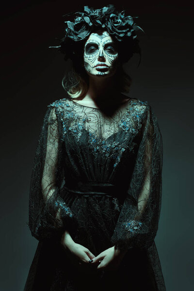 Dia de los muertos. Day of The Dead. Calavera Catrina in the dark. A ray of light falls on her face. Fashion model with sugar skull makeup. Halloween.