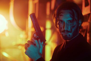 Mafya Savaşları. Yakışıklı, yaralı bir özel ajanın portresi. Şehrin arka sokağında elinde silahla tetikte bekliyor..