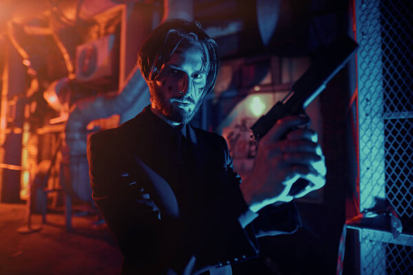 Courageous action hero with a gun in an industrial zone at night. Handsome wounded man special agent.