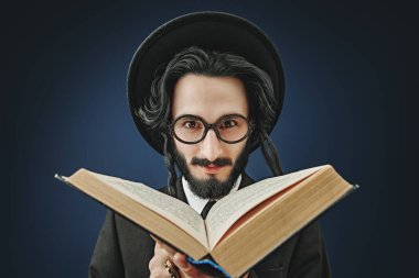 Bir Ortodoks Yahudi Tevrat okur. Stüdyo çekimi koyu mavi arkaplanda. 