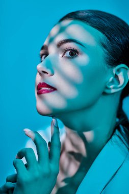 Renkli akuamarin ışıklarıyla poz veren zarif esmer bir kadının portresi. Güzellik. Makyaj ve kozmetik.