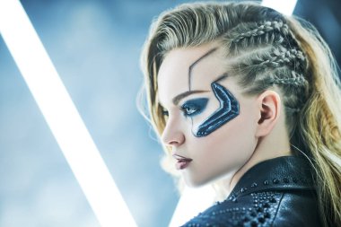 Neon ışıklarının arasında güzel bir bilimkurgu sayborg kızın portresi. Siber punk konsepti. Makyaj ve saç stili.