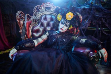 Çekici ve tehlikeli Calavera Catrina terk edilmiş bir kalede eski bir koltukta oturuyor. Kafatası şekeri kız. Ölüler Günü. Dia de los muertos. Cadılar Bayramı.