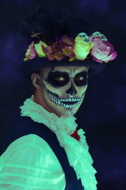 Ölüler Günü. Geleneksel Meksika kostümlü yakışıklı bir adamın portresi. Siyah arka planda şeker kafatası makyajı var. Dia de los muertos. Cadılar Bayramı.