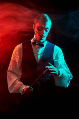 Siyah arka planda gizemli kırmızı ışıklandırmalı kafatası makyajlı yakışıklı bir adam. Dia de los muertos. Ölüler Günü. Cadılar Bayramı.