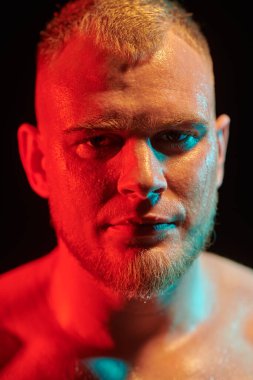 Güçlü ve güçlü bir haltercinin yakın plan portresi kameraya özgüvenle bakıyor. Profesyonel sporlar, şampiyon. Siyah arkaplan. 