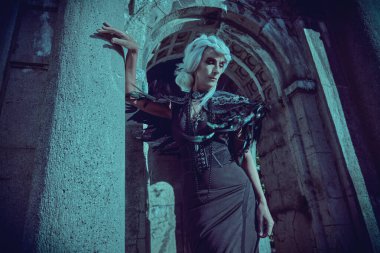 Kara Dul. Güzel gri saçlı ve zengin siyah elbiseli aristokrat bir dul kadın kalenin kemerinde üzgün duruyor. Fantezi Dünyası. Cadılar Bayramı.