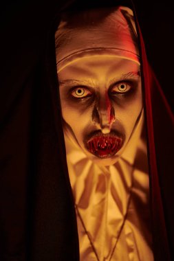 Mum ışığında kanlı dişleri olan şeytani korkunç bir rahibenin yakın plan portresi. Cadılar Bayramı ve Dehşet.