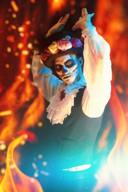 Day of the Dead Carnival. Handsome man in traditional Mexican costume with sugar skull make-up is dancing surrounded by flames. Dia de los muertos. Halloween. clipart