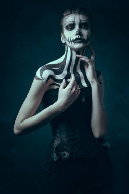 Ölüler Günü ve Cadılar Bayramı. Siyah arka planda kabak kafatası makyajı olan zarif bir kadın.. 