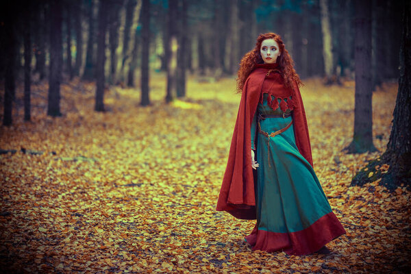 Fantasy world. A beautiful red-haired girl of the Middle Ages walks through the forest. Celtic culture.