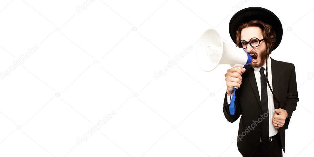 A portrait of an angry male Orthodox Jew who looks at the camera and shouts into the loudspeaker. Studio shot on a white background with copy space. 
