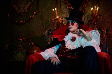 19. yüzyılın yakışıklı aristokratı şık bir takım elbise içinde ve eski kalesinde dudaklarında bir damla kan ile. Kont Drakula. Cadılar Bayramı.