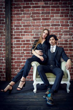 Güzel genç bir kadın çatı katında bir kanepede otururken yakışıklı sevgilisine sarılıyor. Aşk konsepti. 