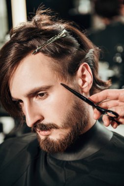 Bir berber dükkanında saçını kestiren yakışıklı bir esmerin yakın plan portresi. Erkek güzelliği ve tarzı. 