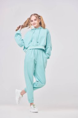 Süslü, parlak kapüşonlu ve beyaz arka planda poz veren hoş bir genç kızın tasviri. Olumlu duygular. Gençlik tarzı. 