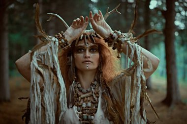 Geleneksel mistik bir şamanik ritüeli, ayin kıyafetleri içindeki kadim bir şaman kadın gerçekleştiriyor. Peri orman cadısı. Fantezi. Cadılar Bayramı. 