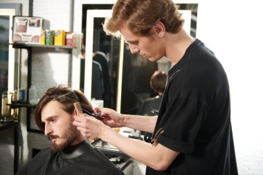 Güzel bir esmer adamın portresi berber dükkanında oturan bir kuaför tarafından tıraş ediliyor.. 