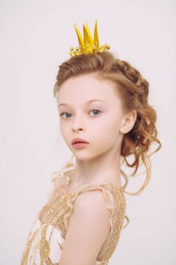 Altın elbiseli ve taç takmış güzel, sarı saçlı küçük prenses kız. Beyaz arka planda stüdyo portresi. Peri masalları. Çocukluk hayalleri. 