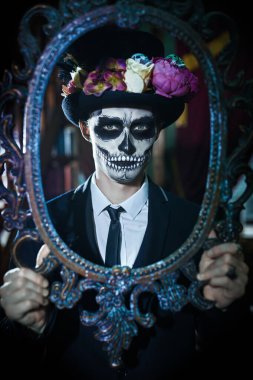 Dia de los muertos. Ölüler Günü. Zarif ve tehlikeli Baron Samedi 'nin portresi eski kaledeki eski bir çerçeveye bakıyor. Kafatası şekeri makyajlı yakışıklı adam. Cadılar Bayramı.